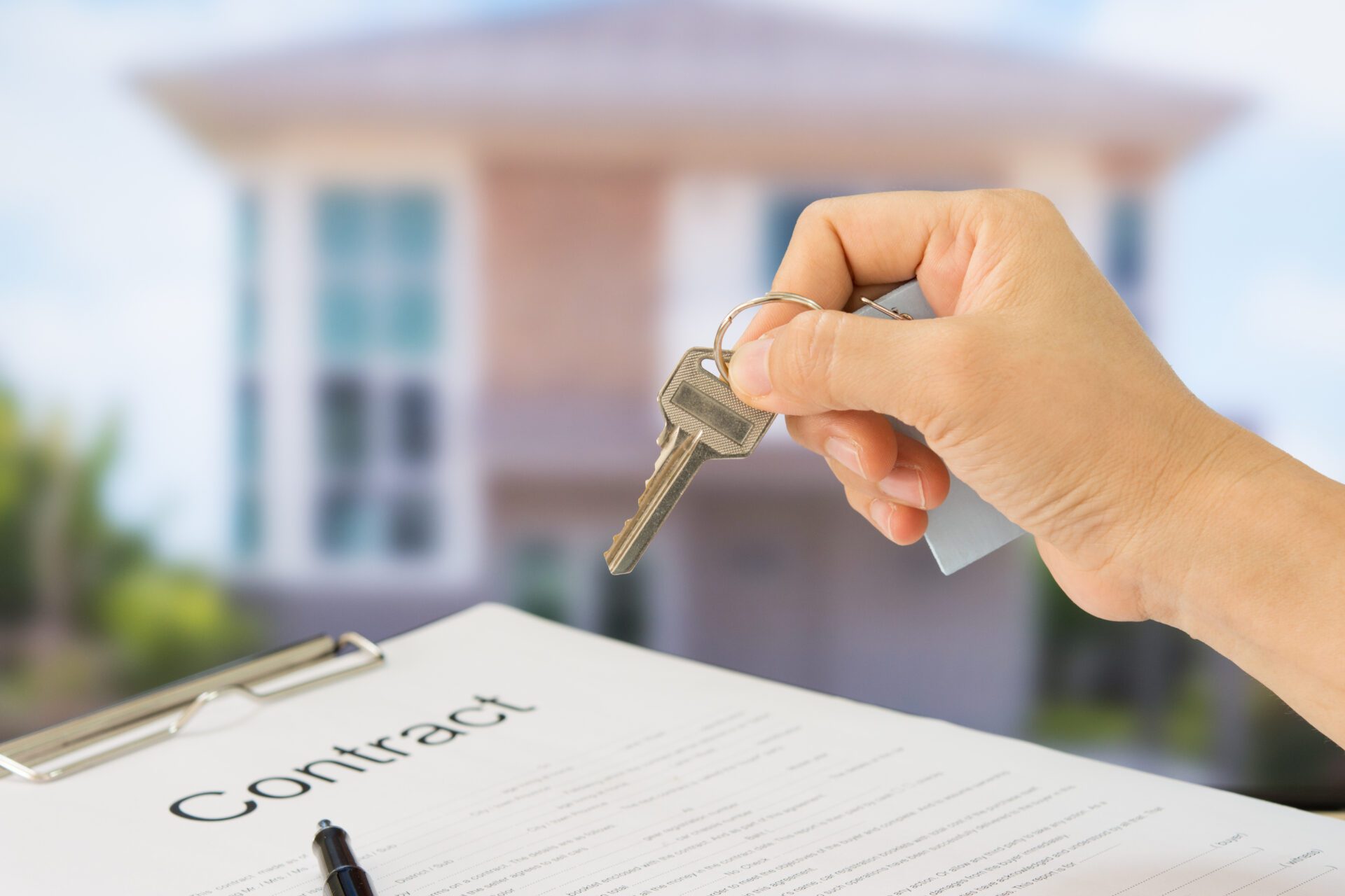Homeowners showing house keys in front of a new home with documents contract. Housing purchase and insurance concept.